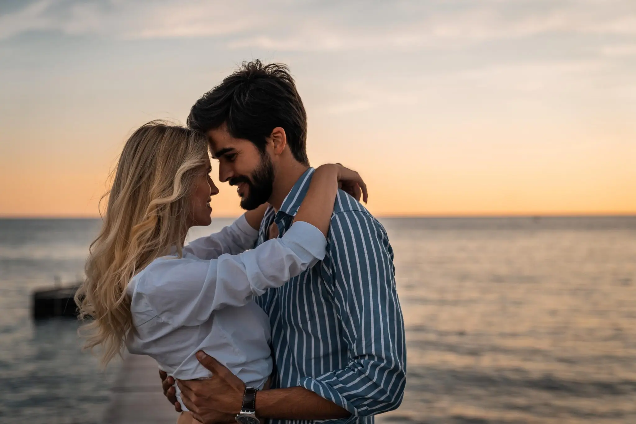 GettyImages-1593793313 A man and woman hugging on the beach.