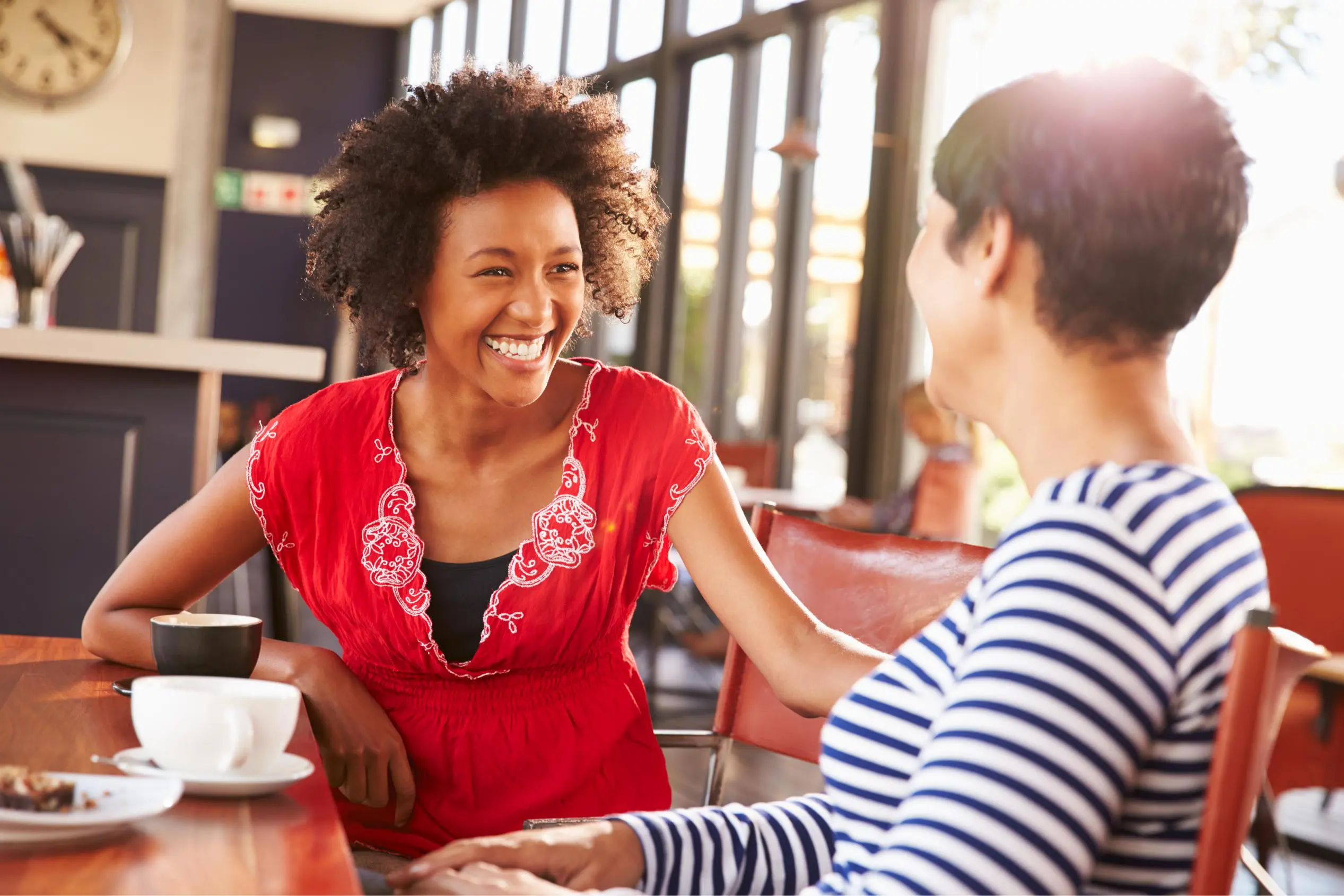Two women are laughing at a table in a restaurant.